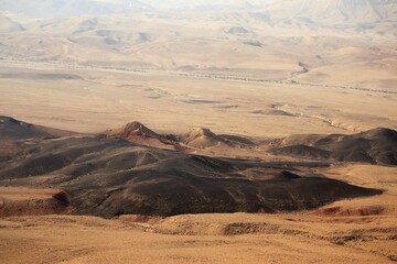 A crater in a desert with its dark hills and bright sand