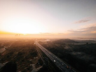 Aerial shot of Malaysian rainforest with a foggy roadway passing through it