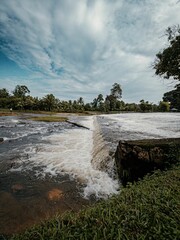 A vibrant powerful waterfall cascading over a rugged dam in a lush, natural environment