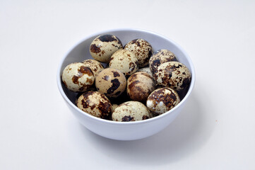 Qual eggs in white bowl selective focus white background