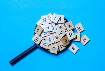 English alphabet made of square wooden tiles with the English alphabet scattered on blue...