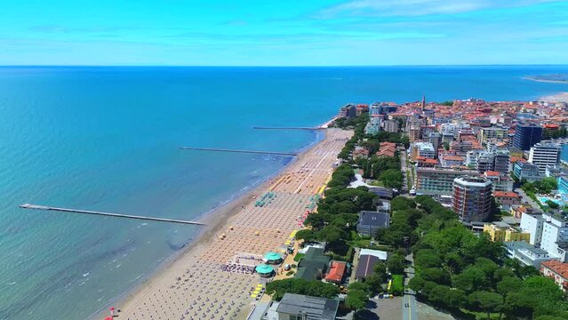 Aerial view of the old city. Roofs of buildings with red tiles and many chimneys. The bell tower of the Catholic Cathedral in the city center. Traveling through narrow streets. Italy Grado 09.2023