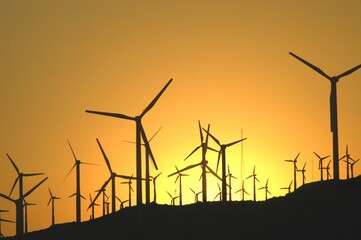 Silhouette of wind turbines silhouetted against a vivid sunset sky in Palm Springs, California.