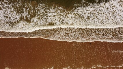 Aerial view of a beach surrounded by the sea in the daylight