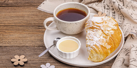Good morning concept. Breakfast with cup of coffee and fresh croissant. Sweet creamy sauce