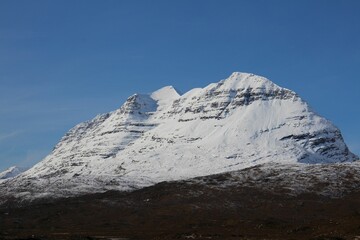 Landscape of the Torridon mountain covered in snow under a blue sky in Scotland