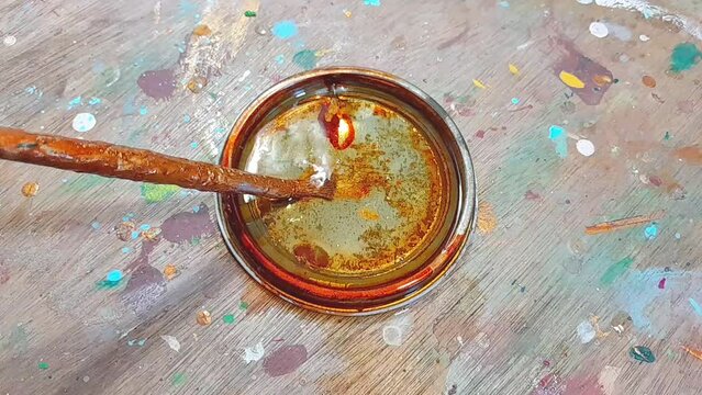 wahsing paint brush with thinner in container at workshop