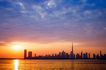 Scenic sunset above a tranquil beach with the Dubai skyline in the background on a summer day