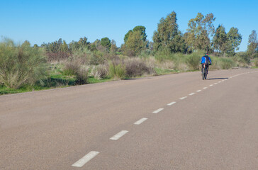 Obraz premium MTB Cyclist speeding down by local road. Vegas Altas irrigation channel roads
