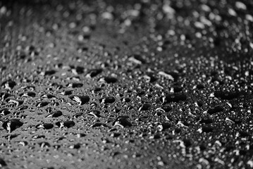 Blurred many rain droplets on a black leather with bokeh light and dark background 