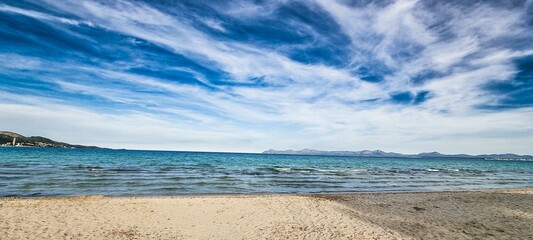 Beautiful blue sky with white clouds above a sandy beach and sea.