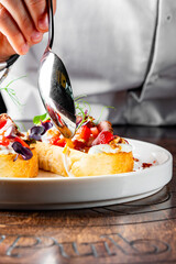 chef hand decorated Strawberry bruschetta with duck meat, goat cheese on plate
