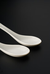 Pure white spoons for serving food on a black background.