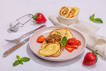 Cottage cheese pancakes, syrniki, curd fritters with strawberry, mint and powdered sugar on plate