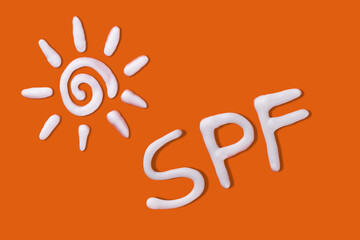 SPF cream. Sunscreen cream in a sun shape on orange background. Creative idea of suntan lotion...