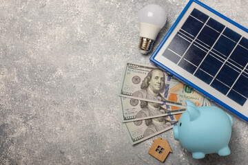 Flat lay composition with solar panel, led lamp and piggy bank on a light texture background. The concept of saving money and clean energy. The concept of ecology and sustainable development.