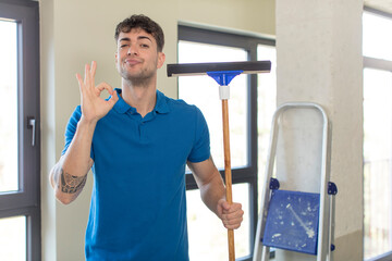 young handsome man feeling happy, showing approval with okay gesture. windows washer concept