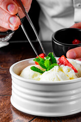 chef hand decorated ice cream in white bowl close up