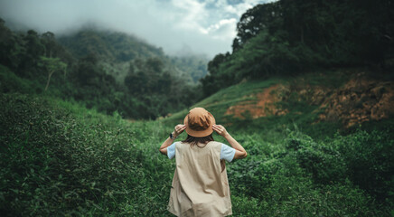 Woman traveler holding hat and looking at amazing mountains and forest, Rest on vacation holiday...