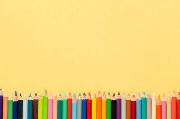 Back to class. Coloured pencils on yellow background. Copy space. Top view.