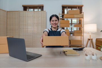 Young business woman working online ecommerce shopping at her shop. Young woman seller prepare parcel box of product for deliver to customer. Online selling, ecommerce