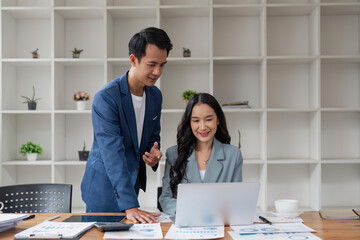 Business man having a discussion with his colleague in an office. Two business people using a laptop in a meeting. Teamwork and collaboration between business professionals