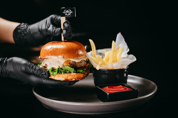 Burger with crispy chicken fillet and fries on a black background