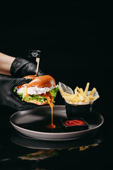 Fish burger with spreads sause on a black background