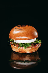 Burger with duck fillet and Camembert cheese on a black background