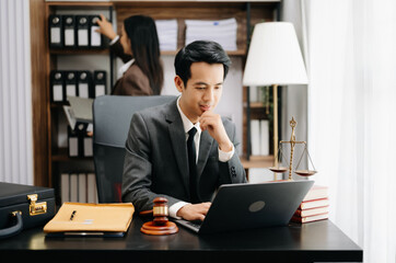 Fototapeta premium Asian lawyer man working with a laptop and tablet in a law office. Legal and legal service concept. Looking at camera in modern office.