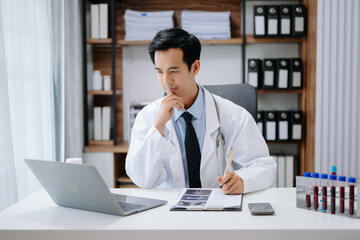 Medical technology concept. Asian Doctor working with mobile phone and stethoscope in modern office