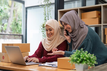 Muslim two woman freelancer sme business online shopping working on laptop computer and checklist order box at home Business online shipping and delivery concept
