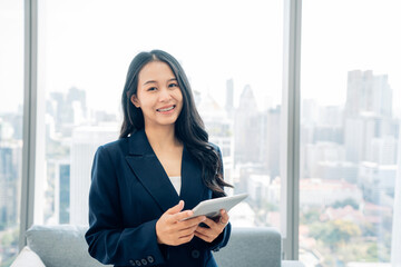 Fototapeta premium Shot of elegant young business woman smiling and using tablet while walking in the office. 