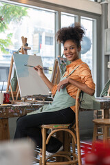 african american female artist painting on canvas doing some art projects on her studio workshop