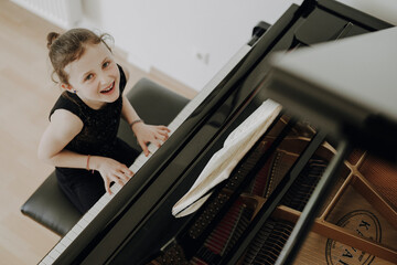 Elegantes Mädchen sitzt am Konzertflügel und spielt Klavier