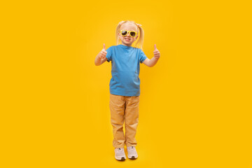 Full-leight portrait of girl in blue T-shirt and sunglasses showing thumbs up. Copy space, mock up