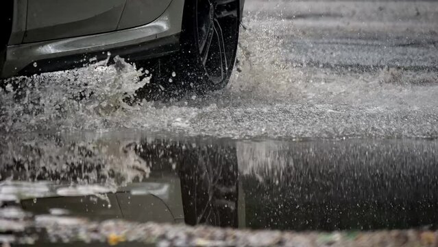 The wheels of the car splash in a puddle after the rain. Slow motion video.