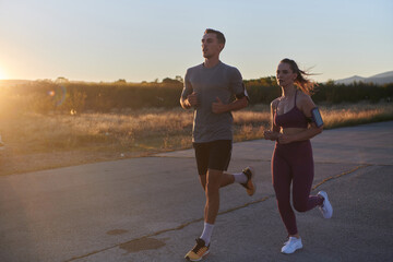 Fototapeta premium A handsome young couple running together during the early morning hours, with the mesmerizing sunrise casting a warm glow, symbolizing their shared love and vitality