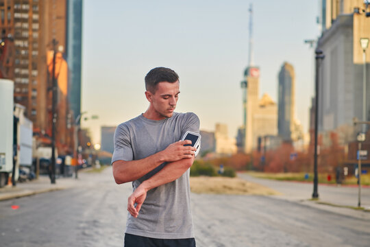 Handsome man checking his smartphone after a morning run on the vibrant streets of New York City, seamlessly blending his active lifestyle with the modern convenience of technology, as he engages with
