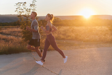 A handsome young couple running together during the early morning hours, with the mesmerizing...