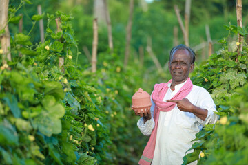 Indian farming happy farmer holding piggy bank in farm, poor farmer, farmer saving