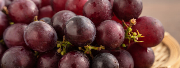 Delicious bunch of grapes fruit on a plate over wooden table background.