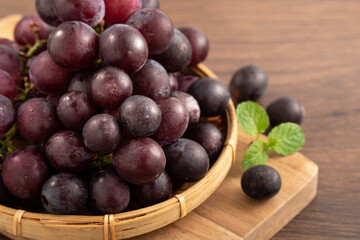 Delicious bunch of grapes fruit on a plate over wooden table background.