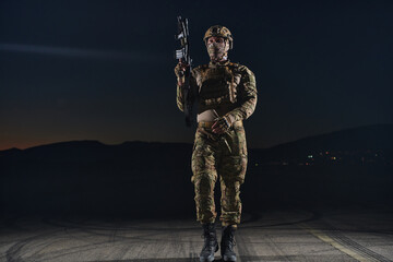 A professional soldier in full military gear striding through the dark night as he embarks on a...