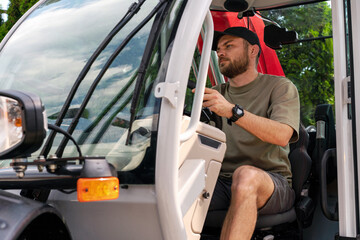 Man worker is operating the agri farmer rotating telescopic handler, sitting in cabin of tele...
