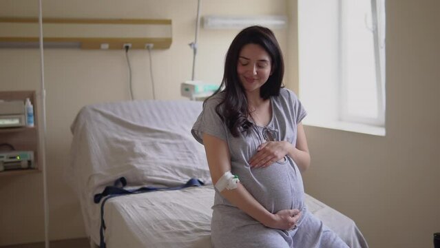 Smiling pregnant woman sitting on couch in hospital room during labor