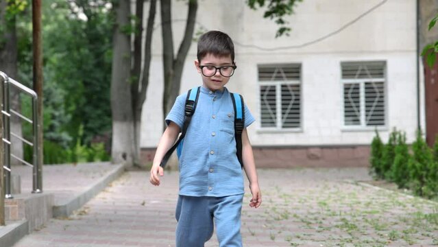 preschooler boy going to school, first day.happy smiling kid with backpack outside against building or wall.back to school 4k 
