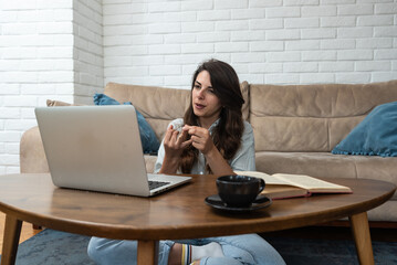 Young smart intelligent student woman sitting at home on floor working as freelancer distant...