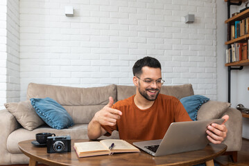 Young smart intelligent student man sitting at home on floor working as freelancer distant foreign...