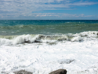 Mediterranean Sea waves crashing over rocks on a beach in stormy weather